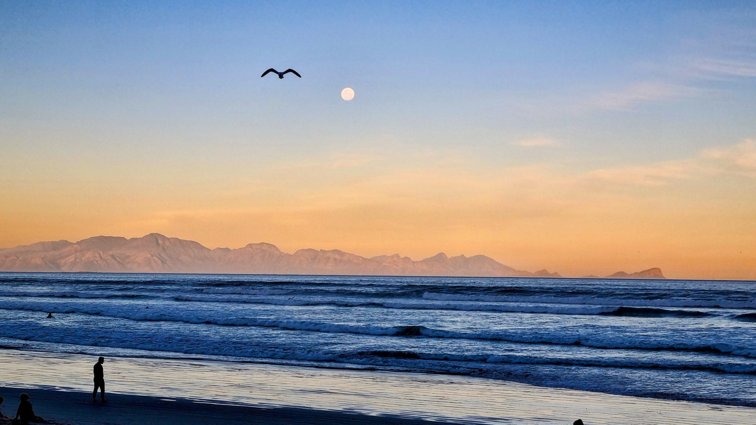 twilight after sunset on the beach and a full moon over the mountains across the bay. Transformational and Inspiring