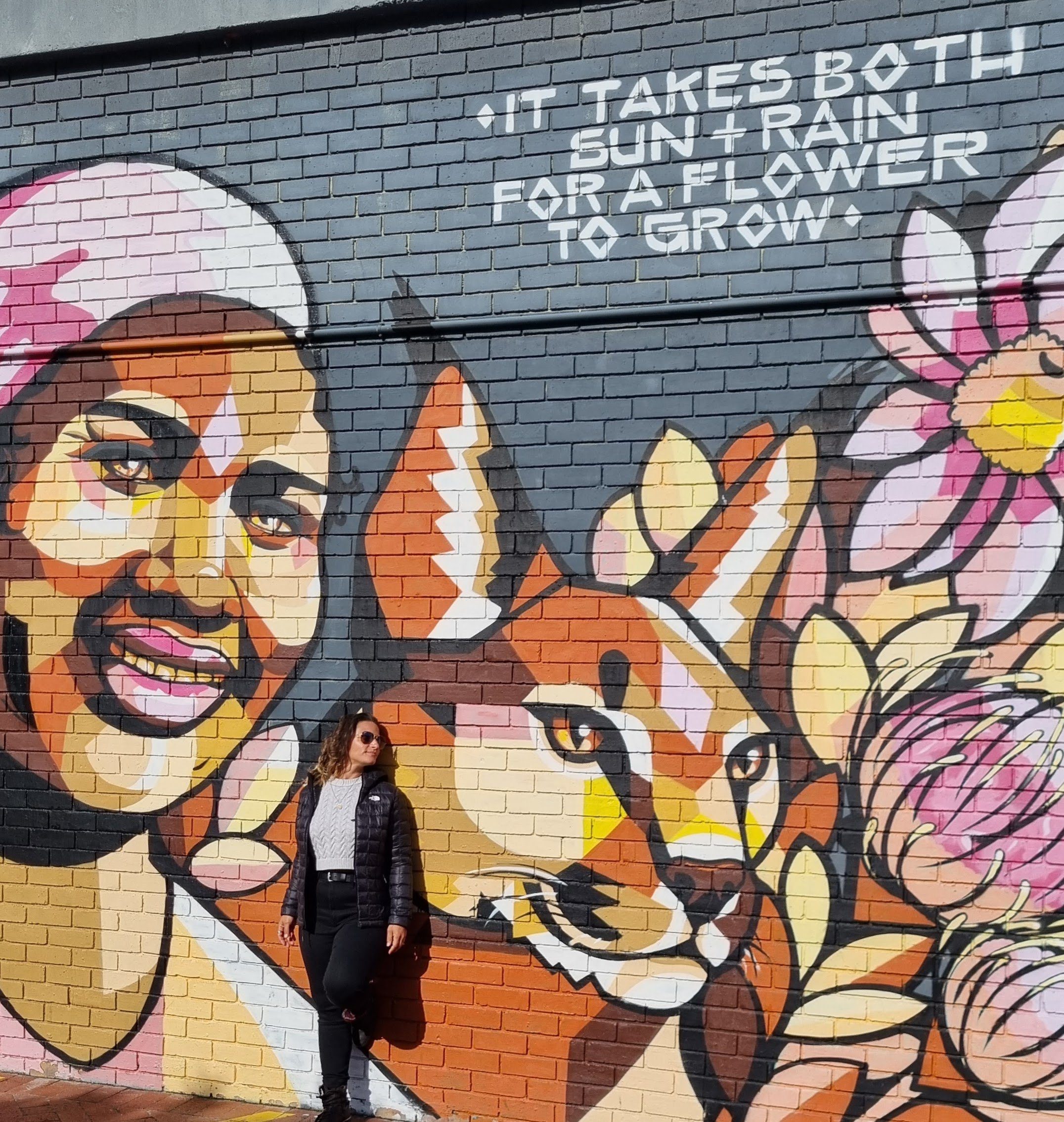 Wall mural of a women a lynx and beautiful flowers with the quote "It takes both sun and rain for a flower to grow."